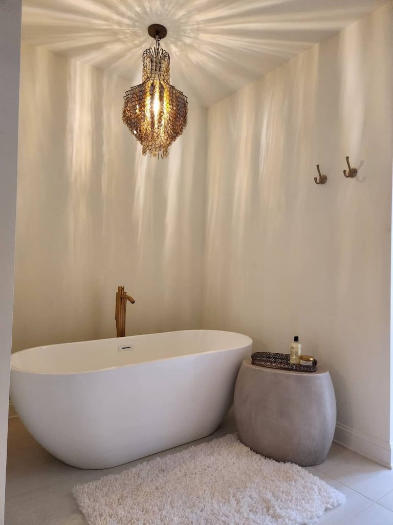 Freestanding bathtub with a decorative chandelier hanging above