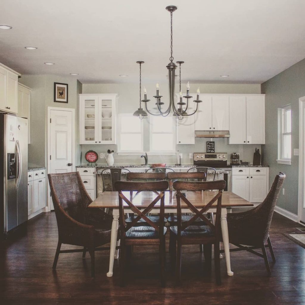White and wood kitchen with a chandelier and farmhouse-style table