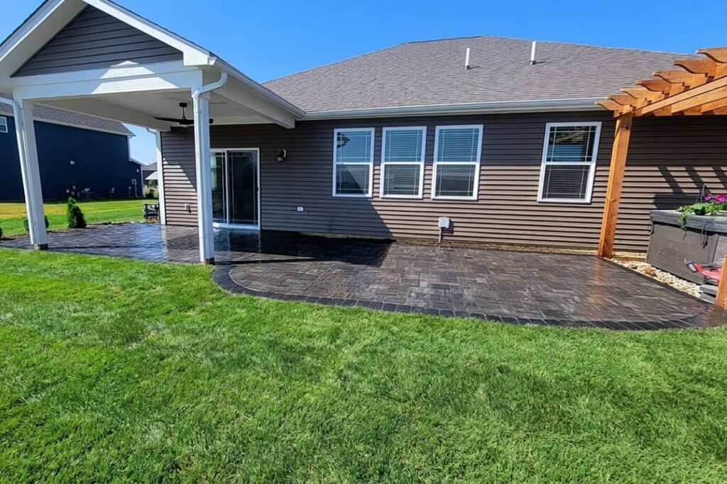Stamped concrete patio with a covered porch, cedar pergola, and spacious backyard designed for outdoor living.