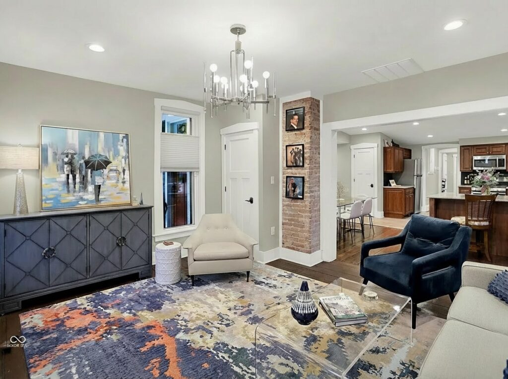 Renovated family room with modern seating, exposed brick, and an open connection to the adjoining kitchen
