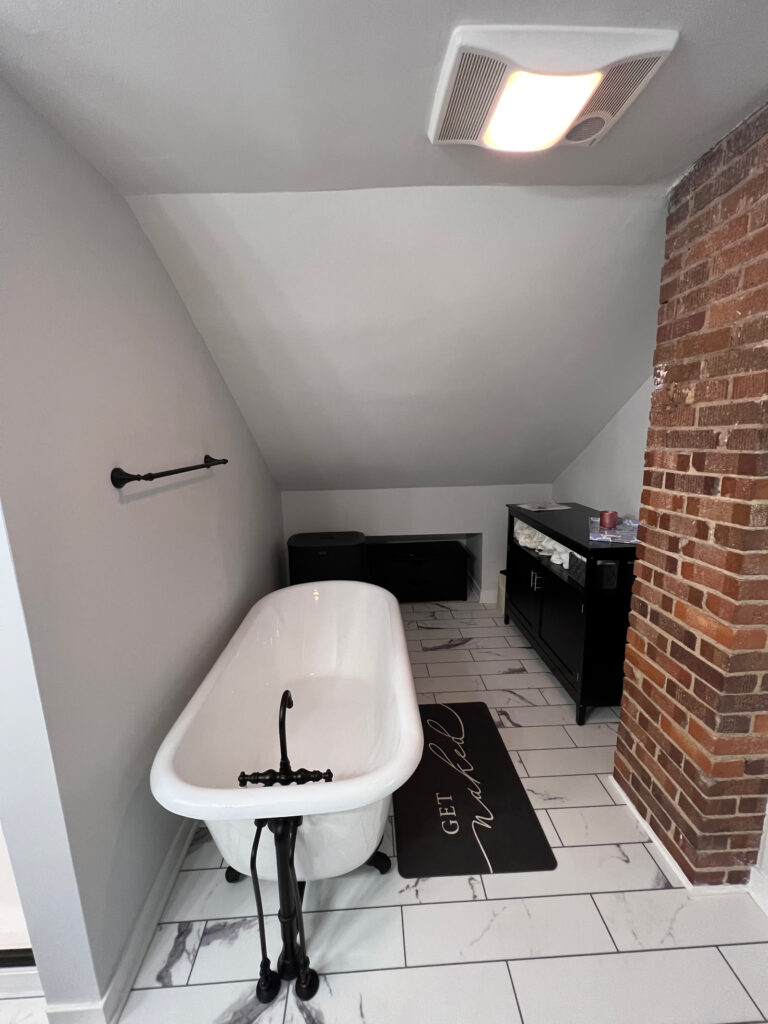 White clawfoot tub with oil-rubbed bronze floor-mounted faucet beneath a sloped ceiling