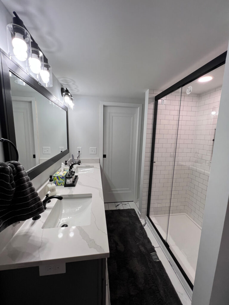 Historic bungalow primary bathroom with a gray double vanity and black-framed walk-in shower