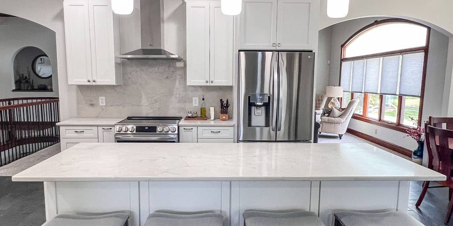 Kitchen remodeling with a large island, stainless steel appliances, and white cabinetry by BGW Construction in Avon.