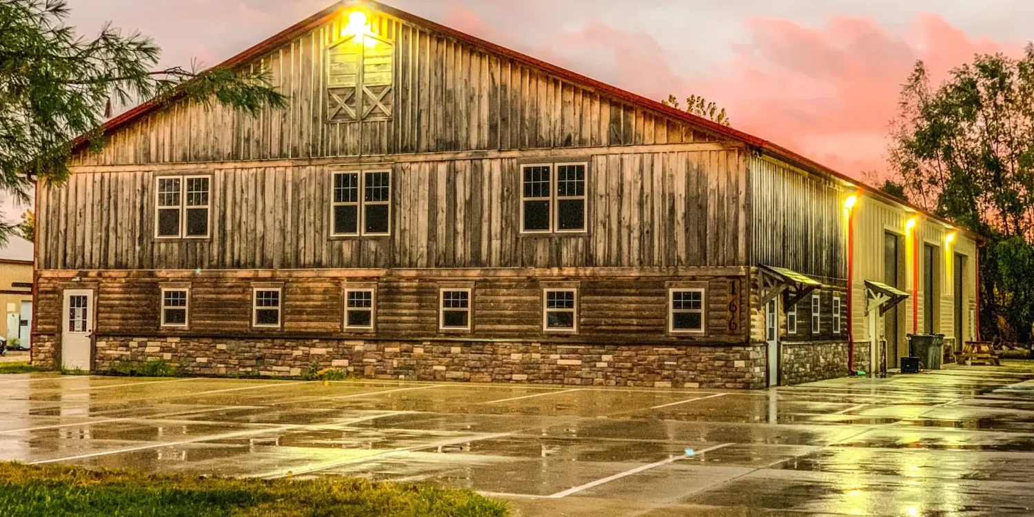 Side view of barn-style office building at dusk with stone accents and lit windows