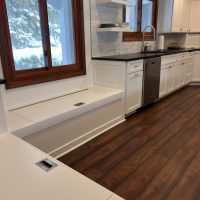 Custom white bench seating with storage under a window in a kitchen nook