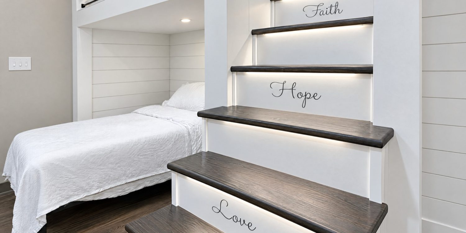 Custom built-in bunk beds by BGW Construction in the DCS safe space at Kingsway Christian Church in Avon, Indiana, with a lit staircase lettered Faith, Hope, Love and 1 Corinthians 13:13