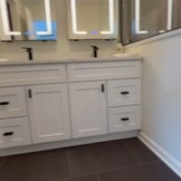 Double sink vanity with white cabinets, black hardware, and dual LED mirrors in a modern bathroom