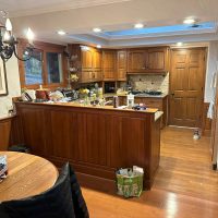 Lake house kitchen with dated wooden cabinets, granite countertops, and mixed lighting, shown before renovation.
