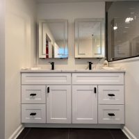 Double sink vanity with white cabinets, black hardware, and dual LED mirrors in a modern bathroom